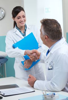 Handshake between a young practitioner and senior doctor.