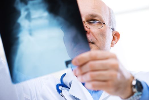 Male senior doctor looking at x-ray images of human spine.