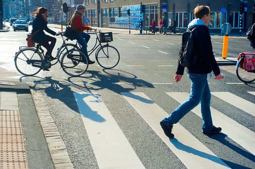 AMSTERDAM, NETHERLANDS - FEB 26, 2014: Unidentified people  crossing the street. It is one of the most cycle-friendly cities in the world. 58% of the citizens uses daily a bicycle.