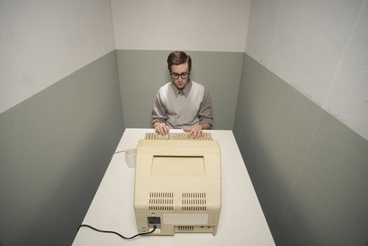 Vintage nerd guy working on old computer in a small room.