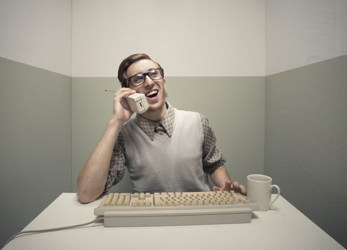 Vintage nerd guy talking on the phone and typing.