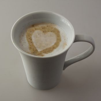 A white cup of cappuccino with white heart of milk