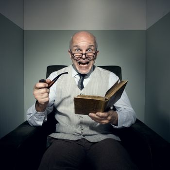 Senior shocked man reading in armchair and smoking pipe.