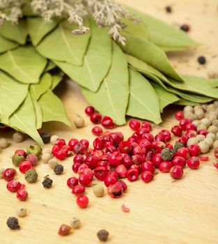 Dry bay laurel leaf with multicolored peppercorn closeup on wooden background