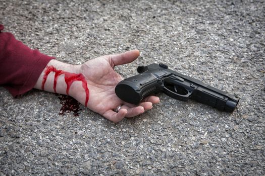 man's hand lying on the floor after suicide with a gun 