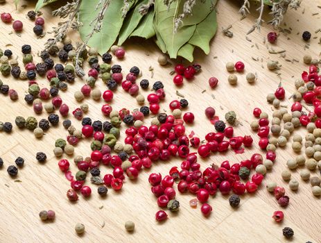 Dry bay laurel leaf with multicolored peppercorn closeup on wooden background