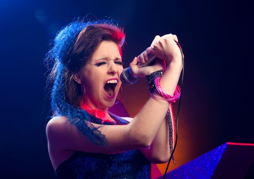 Young pop star girl singing on stage close up.