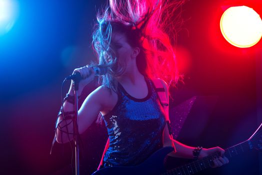 Young rock star singing with stage lights on background.