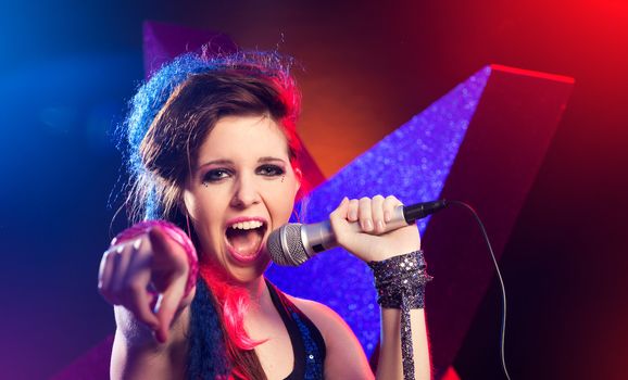 Young pop star girl singing on stage close up.