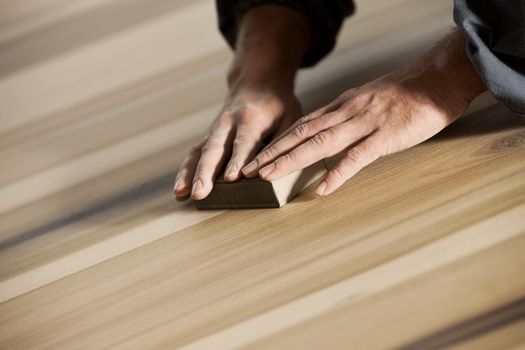 Professional carpenter sanding and refinishing wood surface.