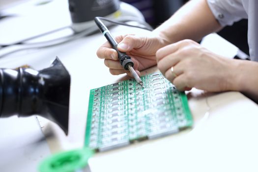 Technician assembling electonic components at his worktable.