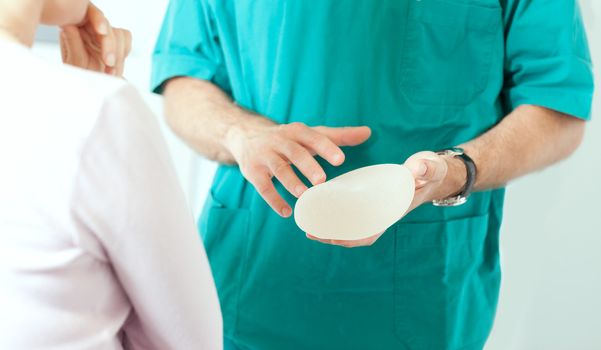 Doctor showing breasts implants to female patient.