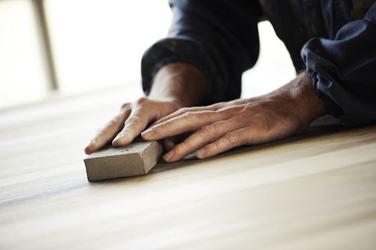 Professional carpenter sanding and refinishing wood surface.