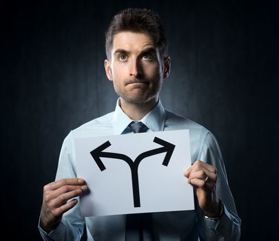 Man holding a sign with directions and pensive expression.