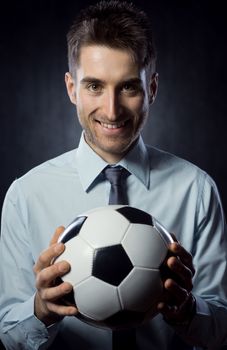 Young attractive businessman holding a soccer ball and smiling.