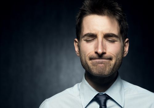 Young man with closed eyes focused on thinking.