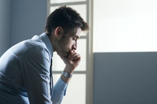 Tired pensive businessman with hand on chin.