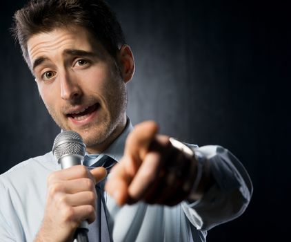 Man giving a speech with microphone and gesturing.