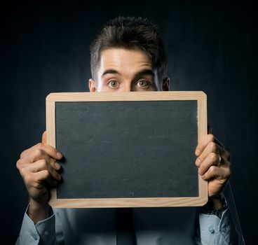 Young handsome man with raised eyebrows holding a blackboard.