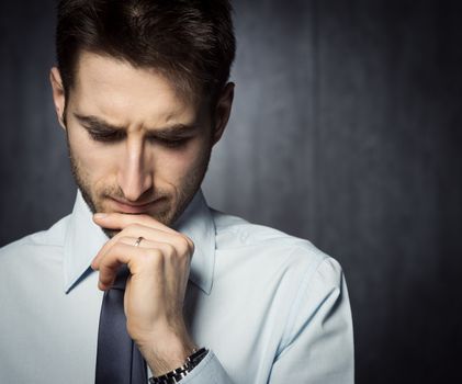 Young handsome businessman thinking with hand on chin.