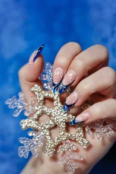 Female hand with beautiful manicure holding a snowflake shot closeup