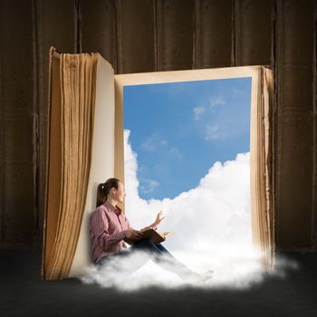 image of a young woman reading a book sitting near a big book