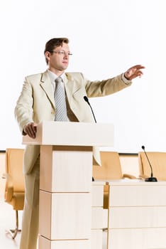 male speaker stands behind a podium on the stage and looking into the hall