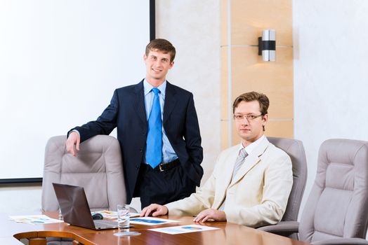 Business people talking, sitting at the table, watching the presentation on a laptop