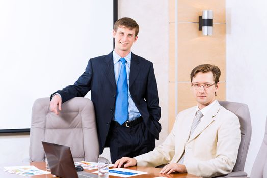 Business people talking, sitting at the table, watching the presentation on a laptop