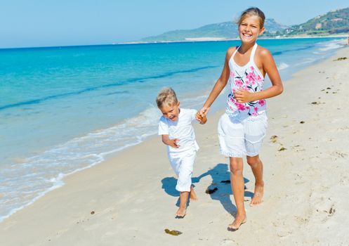 Adorable happy boy and girl running on beach vacation