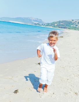 Smiling cute boy runs along the tropical beach.