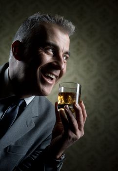 Businessman holding a glass of whisky with vintage wallpaper background.