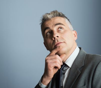 Handsome businessman with hand on chin looking up and thinking.