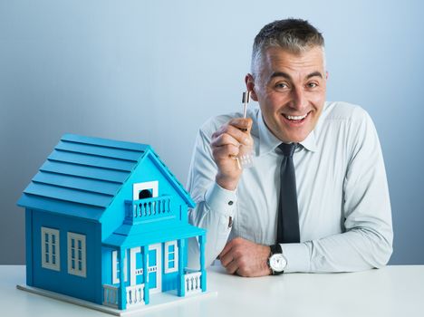 Real estate agent at desk with light blue model house.