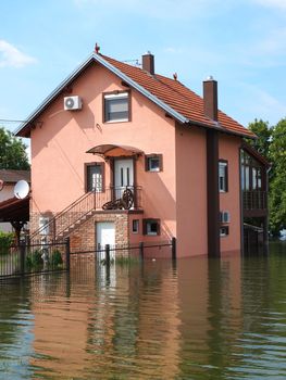 big flooded house with blue sky and white clouds in high water