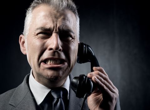 Handsome man holding a vintage phone receiver on dark background.