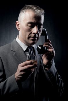 Handsome man holding a vintage phone receiver on dark background.