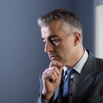 Pensive businessman with hand on chin at office.