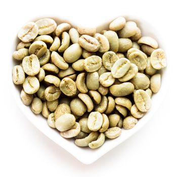 Green coffee beans in the heart shape bowl on a white