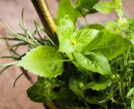 Fresh herbs in the copper mortar on the table