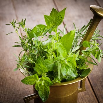 Fresh herbs in the copper mortar on the table