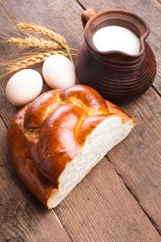 Fresh loaf of challah with milk and eggs on the table