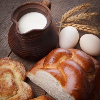 Fresh loaf of challah with milk and eggs on the table