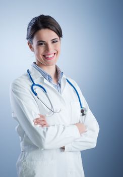 Young female doctor with lab coat and stethoscope posing.