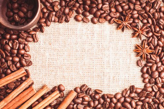 Spilled coffee beans frame with cinnamon and anise