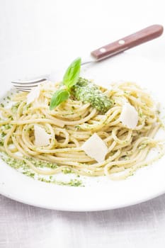 Spaghetti with green pesto and parmesan on the plate