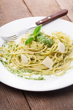 Spaghetti with green pesto and parmesan on the plate