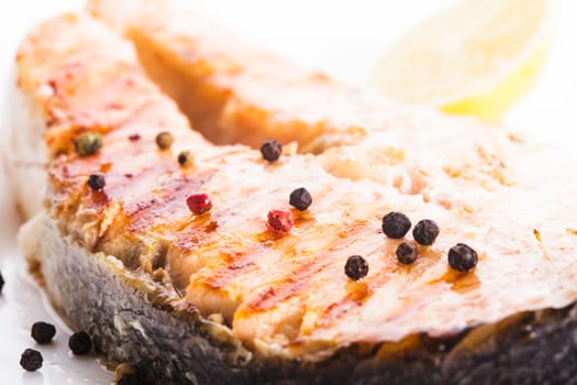 Salmon grilled steak with peppercorn and lemon close up