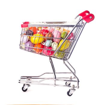 Shopping trolley with many decorative easter eggs on white