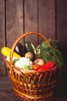 Basket with vegetables and fresh herbs on the wood background